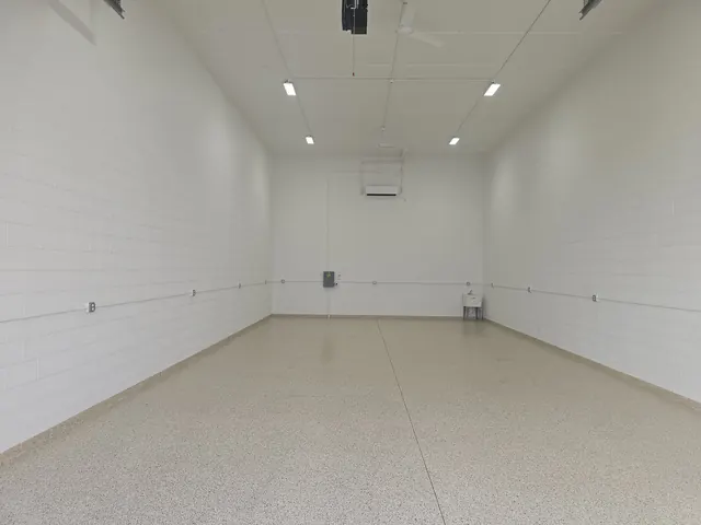 Full-depth view of an empty garage condo with epoxy floor, LED lights and ceiling fans