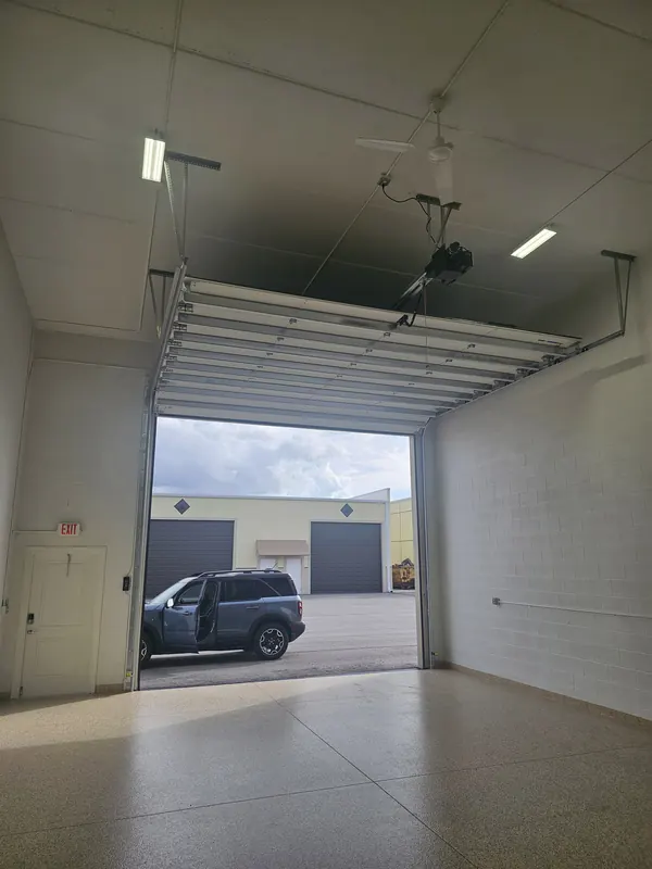 Overhead door open with opener and ceiling fan visible